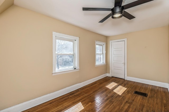 empty room with baseboards, dark wood-style floors, visible vents, and a ceiling fan