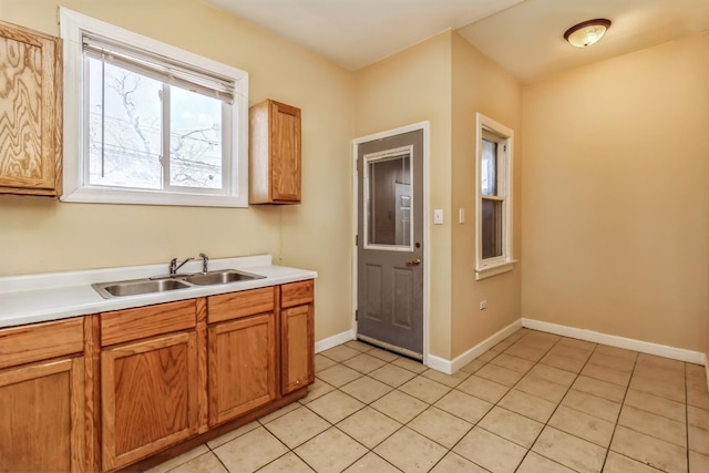kitchen featuring light countertops, a sink, light tile patterned floors, and baseboards
