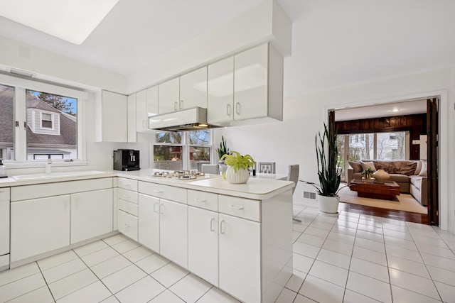 kitchen with under cabinet range hood, a sink, light tile patterned flooring, and light countertops