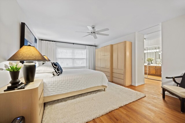 bedroom with ceiling fan, ensuite bathroom, and light wood finished floors