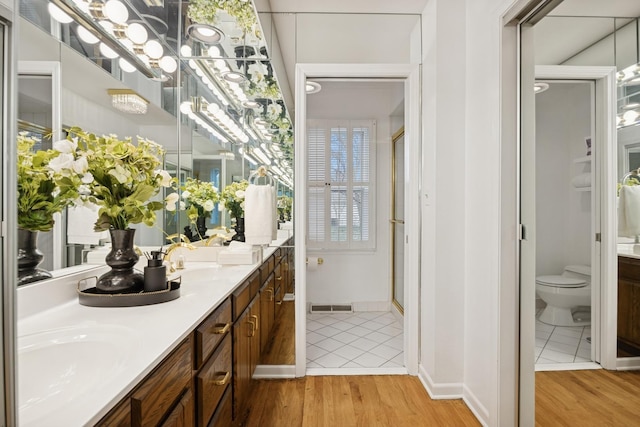 full bathroom with visible vents, wood finished floors, double vanity, and toilet