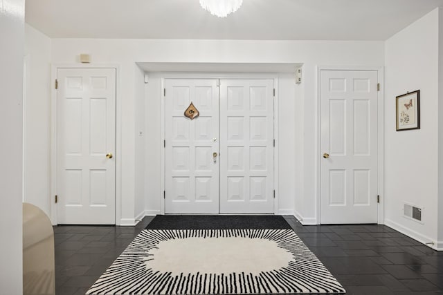 entryway with baseboards, dark tile patterned flooring, and visible vents
