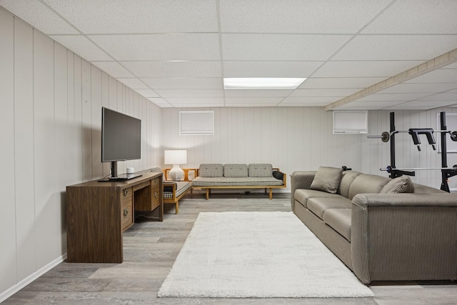 living area featuring baseboards, wood finished floors, and a drop ceiling
