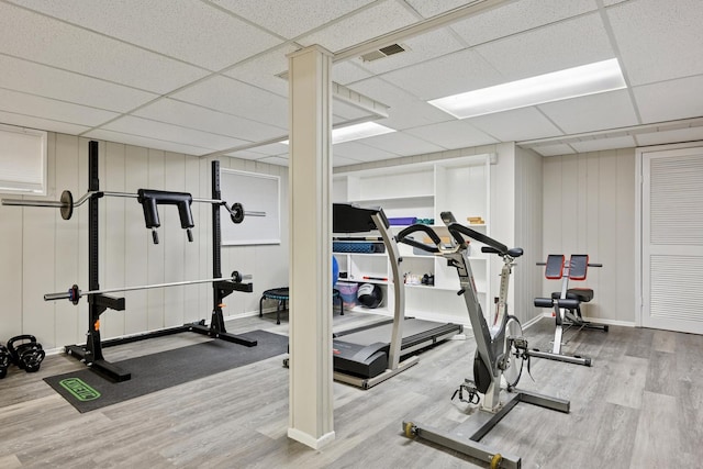 exercise room with wood finished floors, visible vents, a drop ceiling, and baseboards