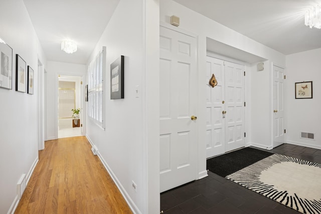 corridor with baseboards, a notable chandelier, and visible vents