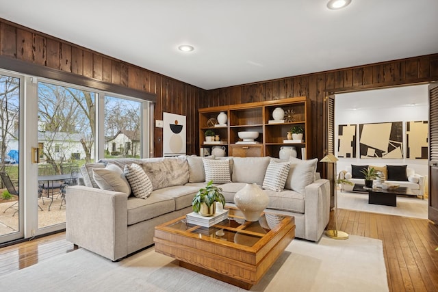 living room featuring recessed lighting, light wood-style flooring, and wood walls