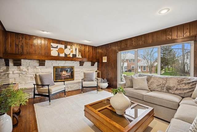living area featuring recessed lighting, light wood-style floors, wooden walls, and a fireplace