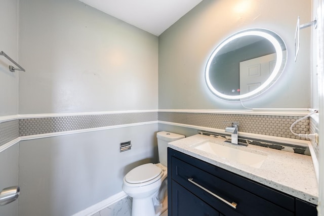 bathroom featuring marble finish floor, vanity, toilet, and decorative backsplash