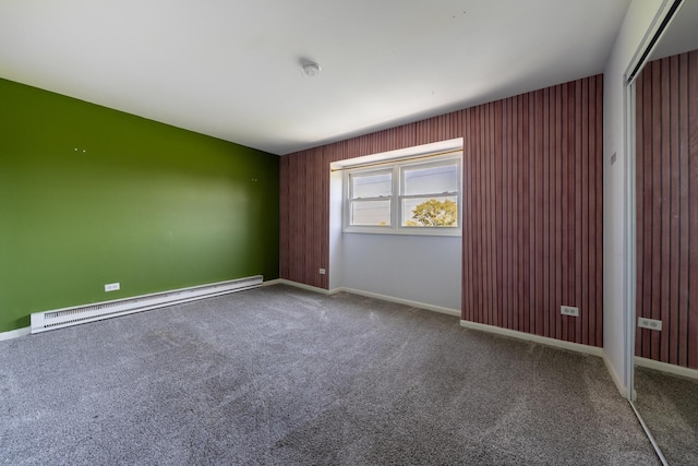 carpeted empty room with a baseboard radiator and baseboards