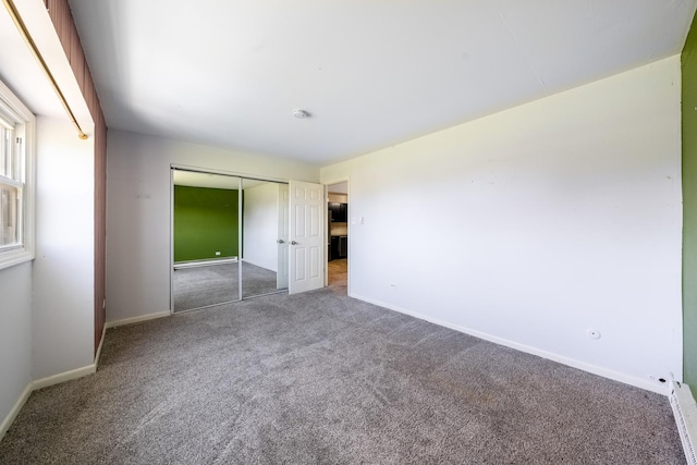 unfurnished bedroom with baseboards, carpet flooring, and a closet