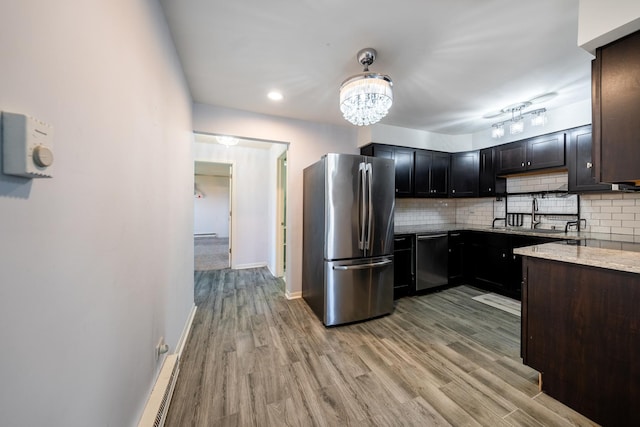 kitchen with stainless steel appliances, light wood-style floors, light stone counters, and tasteful backsplash