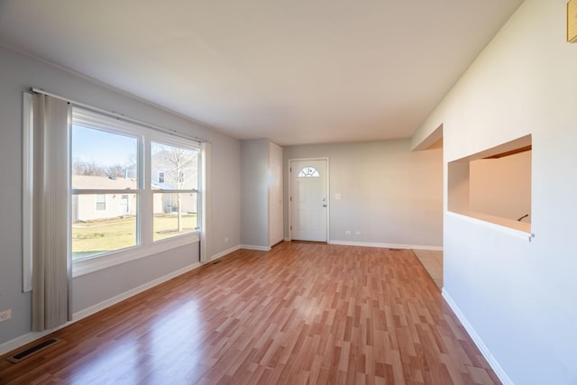 interior space with light wood-type flooring, baseboards, and visible vents