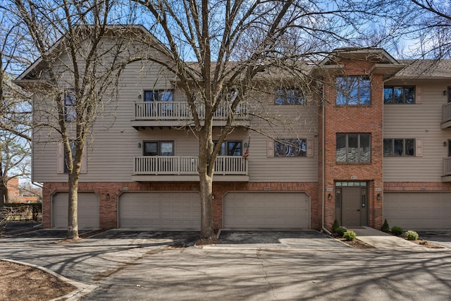 view of property featuring an attached garage, brick siding, and driveway