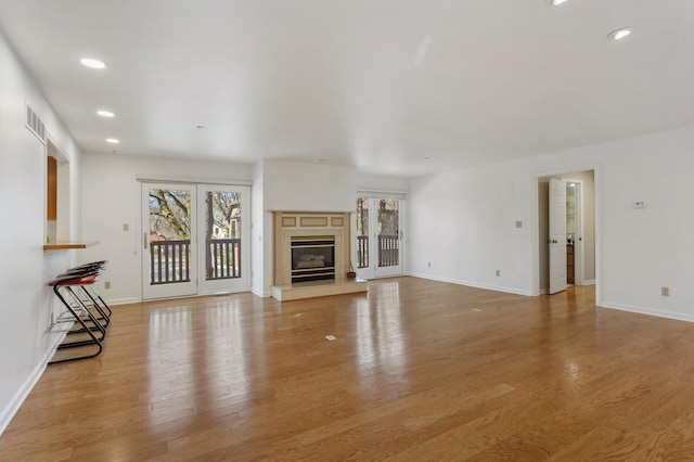 unfurnished living room with baseboards, recessed lighting, and light wood finished floors