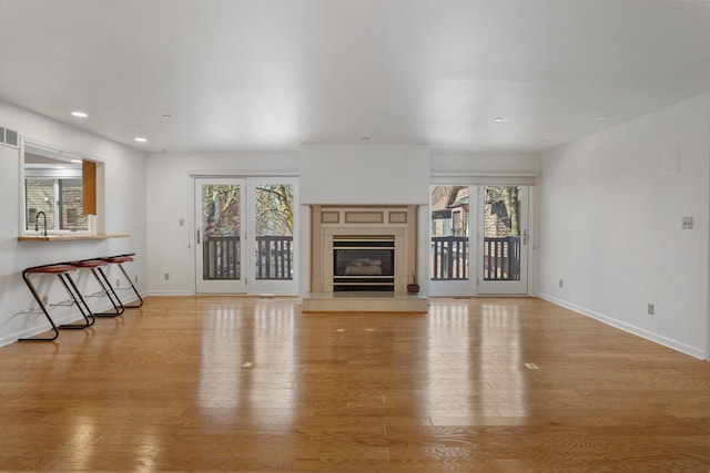 unfurnished living room featuring visible vents, light wood-style flooring, baseboards, a fireplace, and recessed lighting