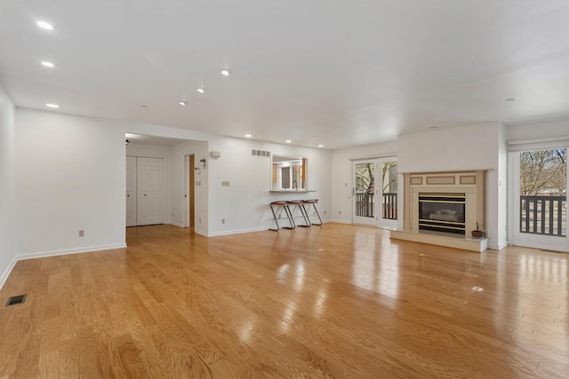unfurnished living room with baseboards, light wood-type flooring, and visible vents