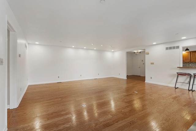 unfurnished living room featuring baseboards, light wood-style flooring, visible vents, and recessed lighting