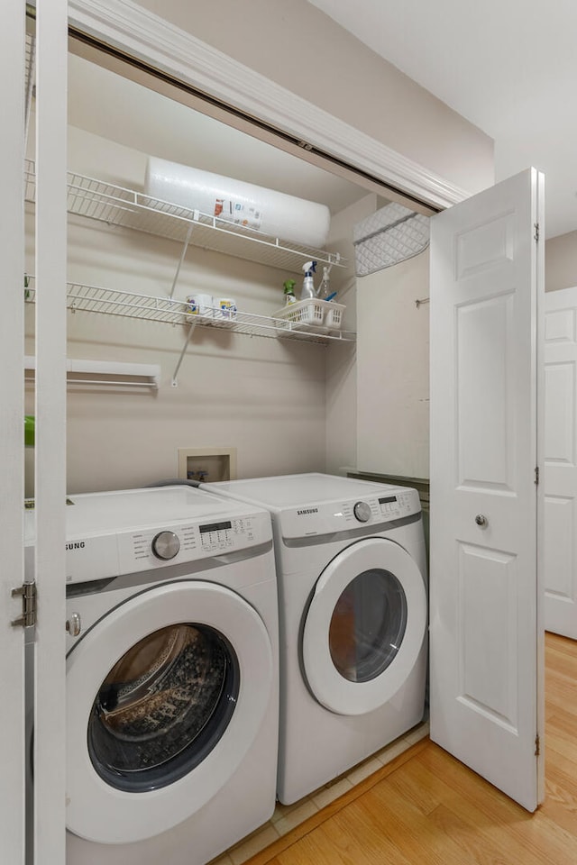 laundry area featuring light wood-type flooring, washing machine and clothes dryer, and laundry area
