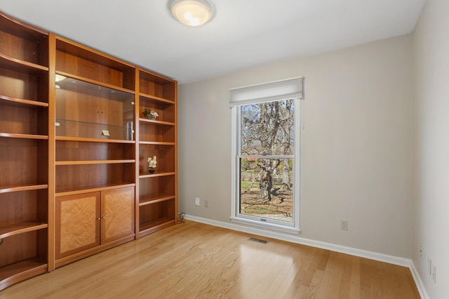 unfurnished room with baseboards, visible vents, and light wood-type flooring