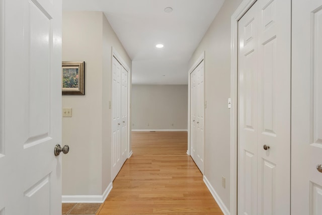 hallway featuring baseboards, light wood-style flooring, and recessed lighting
