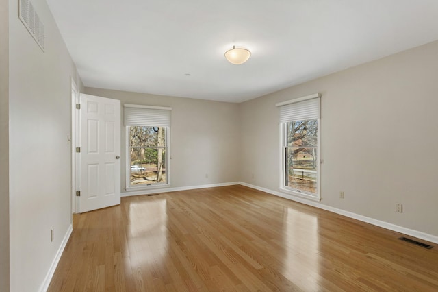 spare room with visible vents, light wood-style flooring, and a healthy amount of sunlight