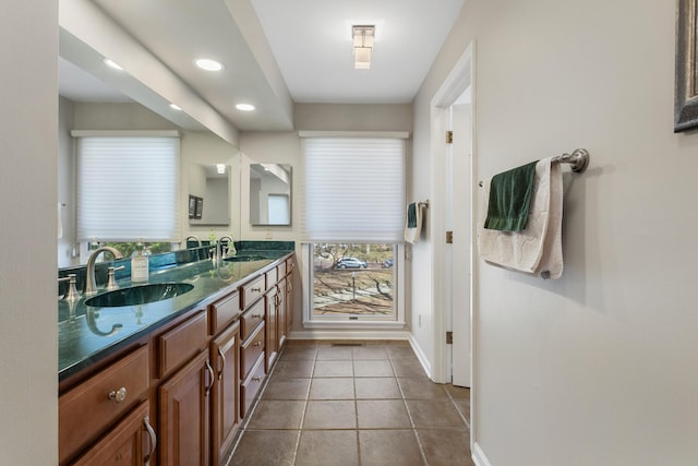 bathroom featuring tile patterned floors, double vanity, a sink, and baseboards