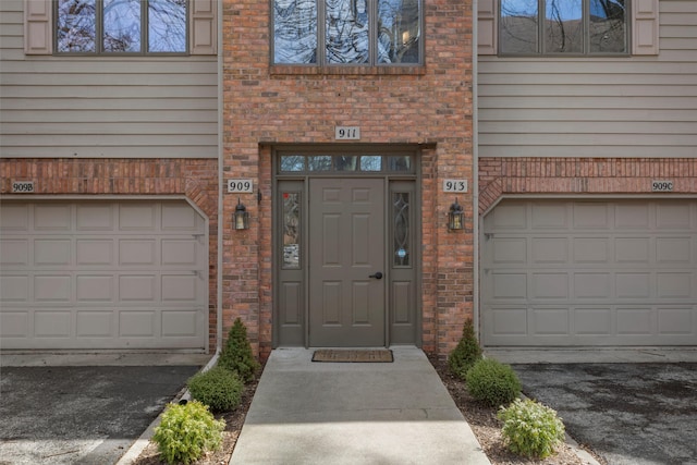 doorway to property featuring brick siding and a garage