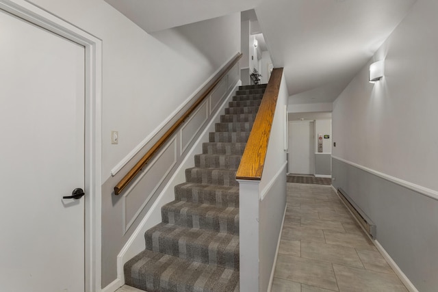 staircase with a baseboard heating unit and tile patterned flooring