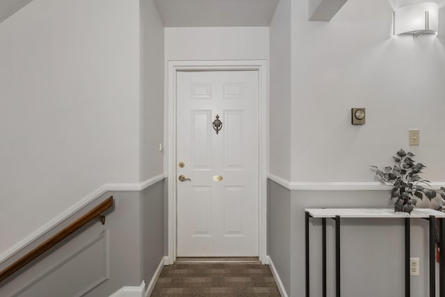 doorway to outside with baseboards and dark carpet