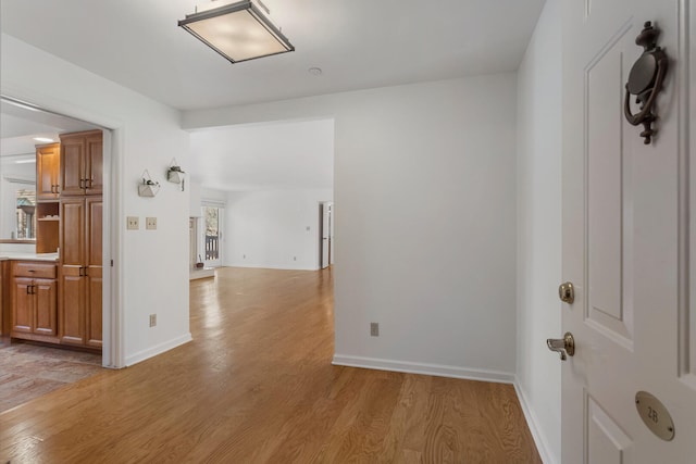 hallway with baseboards and light wood-style floors