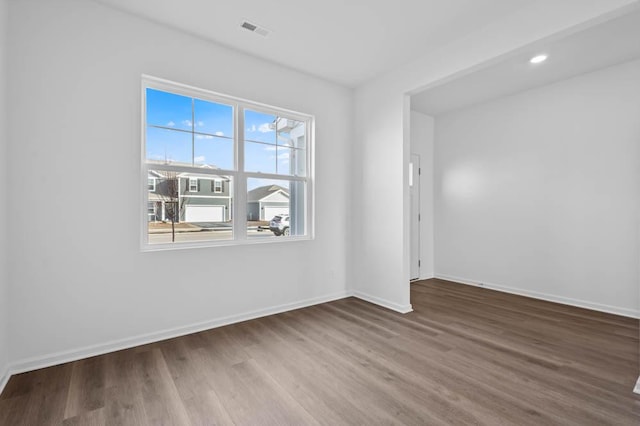 spare room with baseboards, visible vents, and wood finished floors