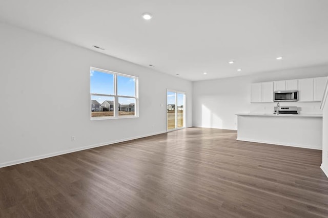 unfurnished living room featuring baseboards, visible vents, recessed lighting, and dark wood-type flooring