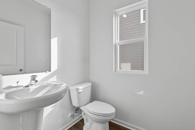 bathroom with toilet, a sink, baseboards, and wood finished floors