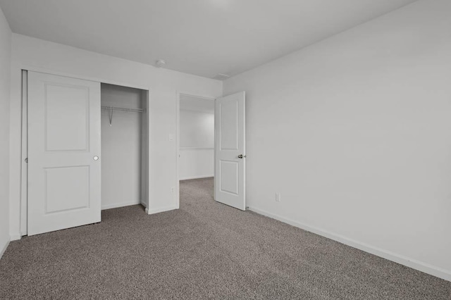 unfurnished bedroom with carpet flooring, baseboards, and a closet
