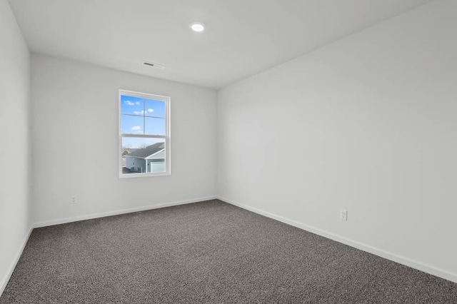empty room with baseboards, dark carpet, and visible vents