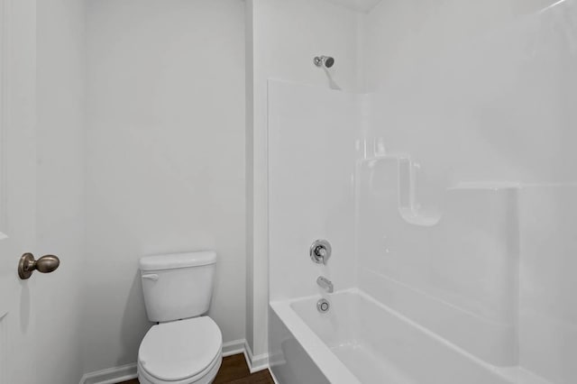 bathroom with baseboards, tub / shower combination, and toilet