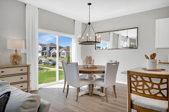 dining space with an inviting chandelier, light wood-style flooring, and baseboards