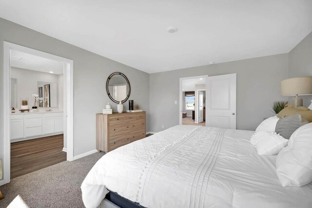 bedroom featuring connected bathroom, baseboards, and carpet flooring