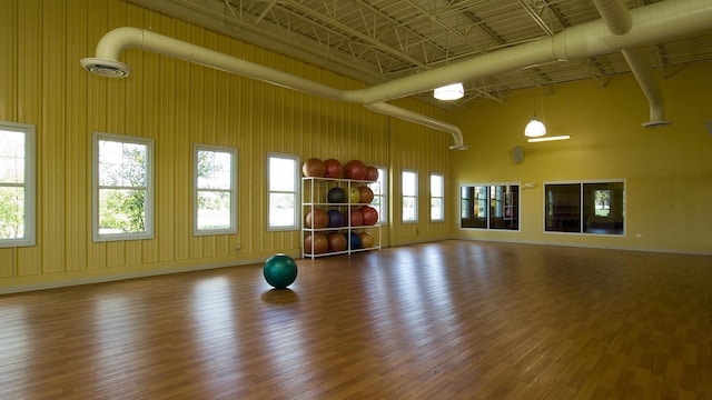 exercise area with a high ceiling, baseboards, and wood finished floors