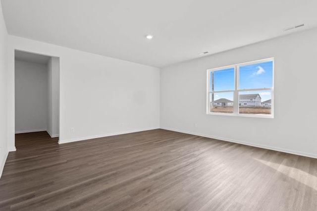 unfurnished room with dark wood-style floors, visible vents, recessed lighting, and baseboards