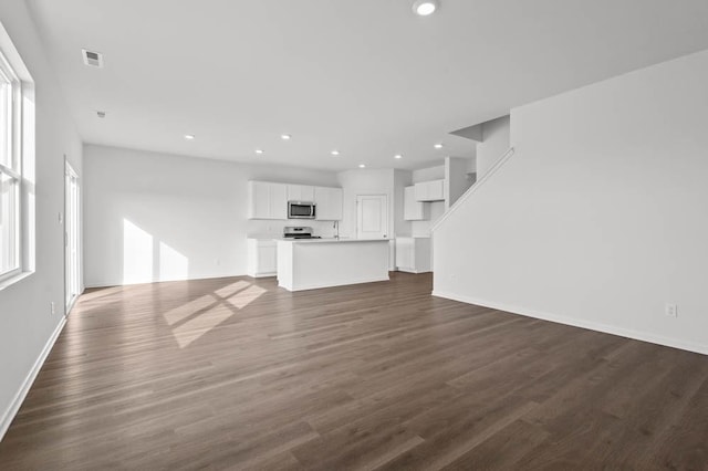 unfurnished living room with dark wood-style floors, visible vents, baseboards, and recessed lighting