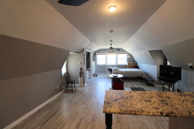 bedroom with baseboards, wood finished floors, vaulted ceiling, and a ceiling fan