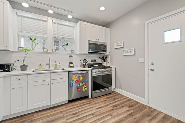 kitchen featuring appliances with stainless steel finishes, a sink, decorative backsplash, and light countertops