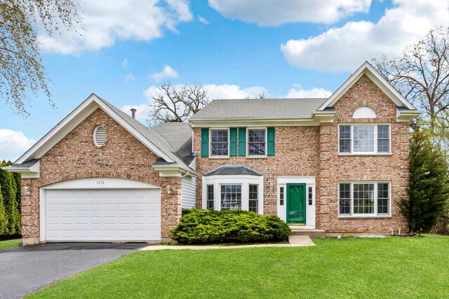 view of front of house with brick siding, a garage, a front yard, and aphalt driveway