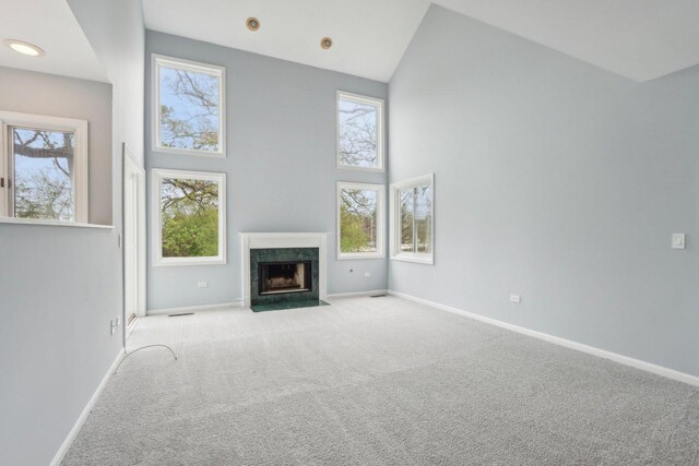 unfurnished living room featuring baseboards, a wealth of natural light, carpet, and a towering ceiling