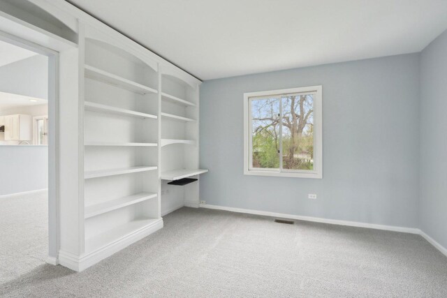 carpeted spare room featuring baseboards and visible vents