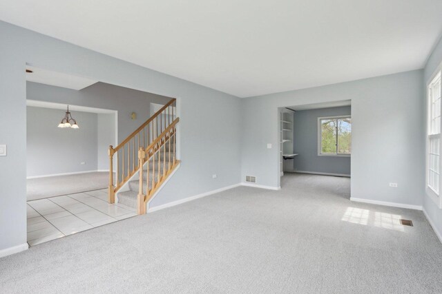 empty room featuring baseboards, carpet flooring, stairs, and a notable chandelier