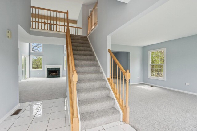 stairs with a fireplace, baseboards, carpet, and visible vents