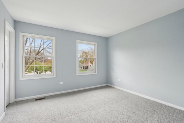spare room with carpet floors, baseboards, and visible vents