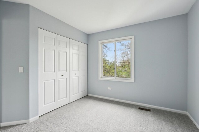 unfurnished bedroom featuring visible vents, carpet, baseboards, and a closet